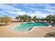 Sparkling blue swimming pool with surrounding desert landscaping including palm trees and a concrete patio at 22717 W Sierra Ridge Way, Wittmann, AZ 85361