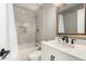 Elegant bathroom featuring tiled shower-tub, white vanity with modern fixtures, and decorative mirror at 2401 E Christy Dr, Phoenix, AZ 85028