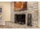 Close-up of stone fireplace with iron screen and tools and a southwestern-style painting hanging above at 2401 E Christy Dr, Phoenix, AZ 85028