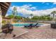 Backyard pool area with lounge chairs, secure fencing, and playground visible in the background at 2401 E Christy Dr, Phoenix, AZ 85028