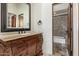 Bathroom vanity with stone countertop, dark wood cabinet, and decorative mirror next to the shower at 3254 N Ladera Cir, Mesa, AZ 85207