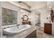 Bathroom featuring a central tub, tiled platform, dual sinks, and natural light at 3254 N Ladera Cir, Mesa, AZ 85207