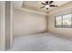 Large bedroom with neutral carpet, a tray ceiling with fan, and a window with blind-style coverings at 3254 N Ladera Cir, Mesa, AZ 85207