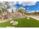 Striking community entrance with decorative stone signage, lush greenery, and mature cacti at 3254 N Ladera Cir, Mesa, AZ 85207