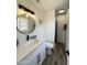 Modern bathroom with a white vanity, round mirror, and gray tile floors at 3748 W Rovey Ave, Phoenix, AZ 85019