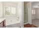 Bathroom featuring a white tub and shower, shuttered window and wood-look floors at 3883 E Santa Fe Ln, Gilbert, AZ 85297