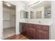 Bathroom with dual sinks, wood cabinets, large mirror, and a walk-in closet at 3883 E Santa Fe Ln, Gilbert, AZ 85297