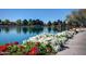 A serene view of the pond surrounded by lush flowers, green trees, and walking path at 3883 E Santa Fe Ln, Gilbert, AZ 85297