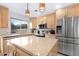 Kitchen island with granite counters, wood cabinets, stainless steel refrigerator, and stainless appliances at 5421 W Brown St, Glendale, AZ 85302