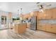 Bright kitchen features natural wood cabinetry, island, stainless appliances, and tile backsplash at 5421 W Brown St, Glendale, AZ 85302