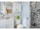 Updated bathroom featuring stylish marble-look tile, modern fixtures, and a decorative plant at 5603 W Bluefield Ave, Glendale, AZ 85308