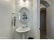 Powder room featuring a pedestal sink, oval mirror, and decorative shelving at 852 E Gary Ln, Phoenix, AZ 85042