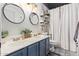 Well-lit bathroom featuring a double sink, stylish mirrors, and decorative shelving for added storage at 18014 N 63Rd Ln, Glendale, AZ 85308