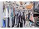 Walk-in closet, filled with colorful organized clothes and accessories on racks and shelves at 18014 N 63Rd Ln, Glendale, AZ 85308