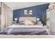 Relaxing main bedroom featuring custom blue accent wall, tufted headboard, and matching dressers at 18014 N 63Rd Ln, Glendale, AZ 85308