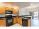 Kitchen featuring wood cabinets, black appliances, granite countertops, and open view to the dining area and balcony at 19700 N 76Th St # 2072, Scottsdale, AZ 85255