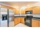 Well-equipped kitchen featuring wood cabinets, stainless steel refrigerator, black appliances, and granite countertops at 19700 N 76Th St # 2072, Scottsdale, AZ 85255