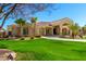 A charming one-story home featuring well-manicured front yard landscaping, mature palm trees, and a circular driveway at 22477 S 197Th Cir, Queen Creek, AZ 85142