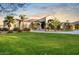 A charming one-story home featuring well-manicured front yard landscaping, mature palm trees, and a circular driveway at 22477 S 197Th Cir, Queen Creek, AZ 85142