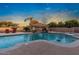 Backyard pool area featuring lounge chairs, a covered patio with a grill, and lush greenery under a clear blue sky at 22477 S 197Th Cir, Queen Creek, AZ 85142