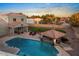 Inviting backyard pool featuring a covered patio, lounge chairs, and lush landscaping under a vibrant sunset sky at 22477 S 197Th Cir, Queen Creek, AZ 85142