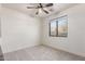 Cozy bedroom with neutral carpet, white walls, a ceiling fan, and a well-lit view to the exterior at 37327 N 16Th St, Phoenix, AZ 85086