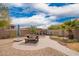 Well-kept backyard featuring picnic table, covered patio seating, fire pit, and desert plants at 41219 W Brandt Dr, Maricopa, AZ 85138