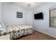 Bright bedroom with a mounted TV and a bed with a floral sunflower patterned cover at 41219 W Brandt Dr, Maricopa, AZ 85138