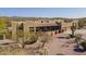 Aerial view of a desert home with a tile roof, three-car garage, lush landscaping and mountain views at 4185 S Redtail Trl, Gold Canyon, AZ 85118