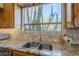 Functional kitchen sink with granite countertops, wooden cabinets, and a view of the desert landscape through the window at 4185 S Redtail Trl, Gold Canyon, AZ 85118