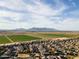 A wide aerial shot over houses towards distant fields and mountain landscape at 44250 W Vineyard St, Maricopa, AZ 85139