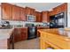 Functional kitchen with wooden cabinets, and black appliances at 44250 W Vineyard St, Maricopa, AZ 85139