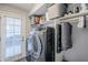 Modern laundry room with front loading washer and dryer, shelving, and access to the backyard at 5507 E Grandview Rd, Scottsdale, AZ 85254