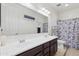 Spacious bathroom with double sinks, dark wood cabinets, large mirror, toilet and patterned shower curtain at 676 N 156Th Ln, Goodyear, AZ 85338