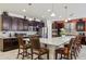 Open-concept kitchen with an eat-in island, stainless steel appliances, and dark cabinets at 676 N 156Th Ln, Goodyear, AZ 85338