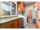 Bright laundry room, featuring wood cabinets, granite countertop, and modern washer/dryer at 10425 N 23Rd St, Phoenix, AZ 85028