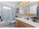 Bright bathroom with a wood vanity, white countertop, decorative mirror, and bathtub with a shower at 16302 N 36Th Ave, Phoenix, AZ 85053