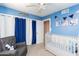 Bright bedroom with blue walls, ceiling fan, gray chair and a white crib at 16302 N 36Th Ave, Phoenix, AZ 85053