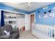 Bright bedroom with blue walls, ceiling fan, white trim, white closet, and a white crib at 16302 N 36Th Ave, Phoenix, AZ 85053