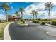 Community entrance with lush landscaping, palm trees, and beautiful gate house on a sunny day at 20208 N Oxbow Ln, Maricopa, AZ 85138