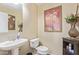 Compact powder room with pedestal sink, toilet, and decor on the walls and shelving at 3209 W Apollo Rd, Phoenix, AZ 85041