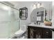 Well-lit bathroom with a framed mirror, dark vanity, frosted glass shower, and floating shelf at 5114 W Corrine Dr, Glendale, AZ 85304