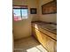 Bright laundry room featuring tile floors, wood cabinets, sink, and a window offering an outdoor view at 55823 N 329Th Dr, Wickenburg, AZ 85390