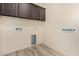 Bright laundry room with dark brown cabinets and wood-look floors at 10012 E Tamery Ave, Mesa, AZ 85212