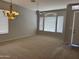 A naturally lit, carpeted living room enhanced by a stylish chandelier and neutral decor at 1022 E Hiddenview Dr, Phoenix, AZ 85048