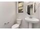 Powder room with a pedestal sink, round mirror, modern fixtures, and neutral color palette at 2828 N Evergreen St, Buckeye, AZ 85396