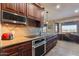 A kitchen with dark wood cabinets, stainless steel appliances, and a breakfast bar with a desk area at 15838 E Thistle Dr, Fountain Hills, AZ 85268