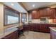 A kitchen with dark wood cabinets and granite countertops also featuring a desk and view of the landscape at 15838 E Thistle Dr, Fountain Hills, AZ 85268