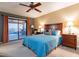 A bedroom with a blue quilt on the bed, with lamps on the nightstands, and a sliding door to the patio at 15838 E Thistle Dr, Fountain Hills, AZ 85268