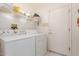 Bright laundry room featuring a washer, dryer, storage shelf and a white door at 22801 N Las Vegas Dr, Sun City West, AZ 85375